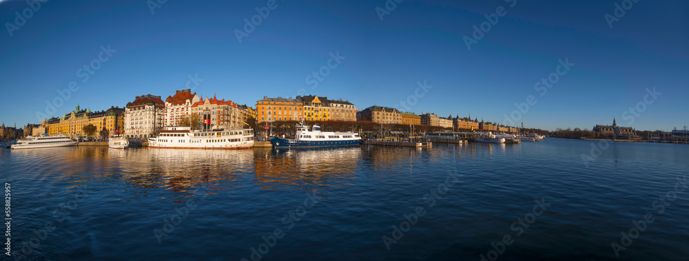 Fototapeta premium Moored boats at the pier Strandvägen in the bay Ladugårdsviken, a low winter solstice a sunny and snowy day in Stockholm