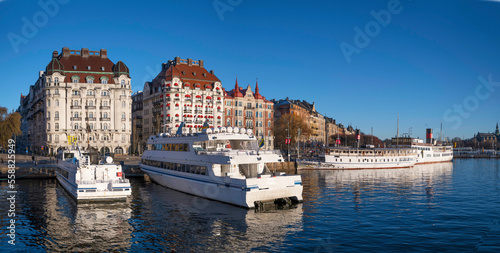 Moored boats at the pier Strandvägen in the bay Ladugårdsviken, a low winter solstice a sunny and snowy day in Stockholm