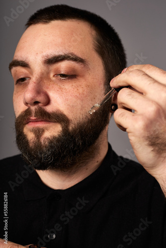 Beard care. Closeup of male face and pipette with a oil for a beard growth