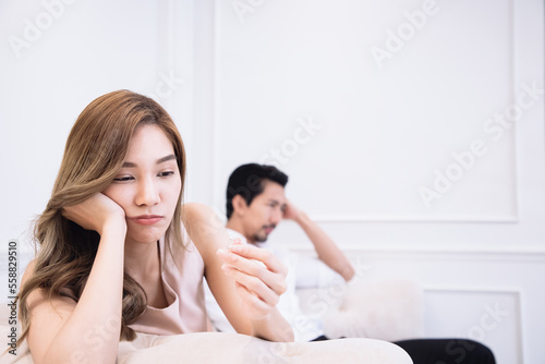 Depressed sad young Asian woman wife sit with boyfriends on sofa and holding engagement wedding ring in hand feeling upset disappointed frustrated unhappy regret marriage mistake suffer from break up