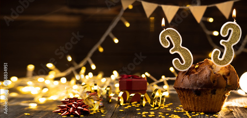 Canvas Print Number 33 birthday celebration candle in cupcake against lights and wooden background