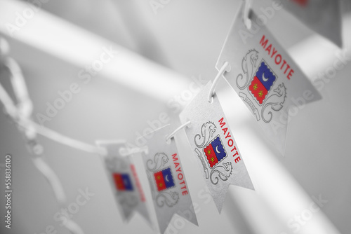 A garland of Mayotte national flags on an abstract blurred background photo