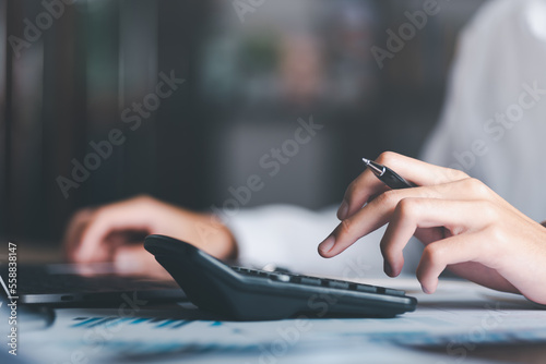 Businessman calculating figures in company financial documents with a calculator,analysis of company financial data,Planning to assess and review budgets,concept of finance and investment photo