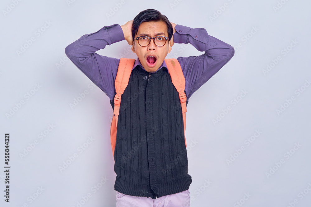 Shocked young Asian student man 20s wearing casual clothes with backpack put his hand on his head and looking at camera isolated on gray background. Education in high school university college concept Shocked young Asian student man 20s wearing casual clothes with backpack put his hand on his head and looking at camera isolated on gray background. Education in high school university college concept