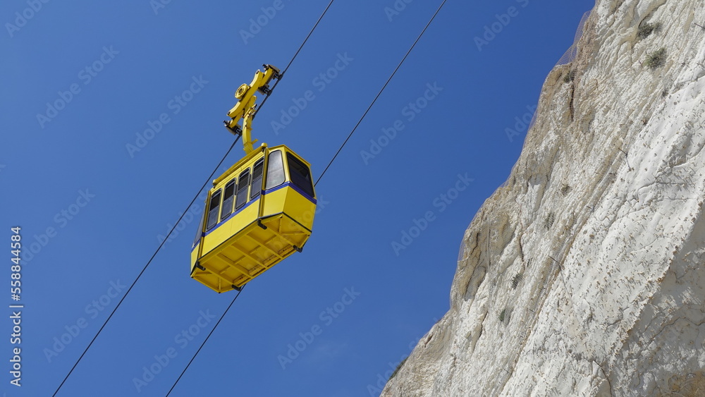 Yellow funicular car against the background of the sky and white rock in the village of Rosh ha nikra in the north of Israel. Yellow funicular car against the background of the sky and white rock in the village of Rosh ha nikra in the north of Israel.