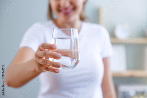 Young woman showing a full glass of water in her hand