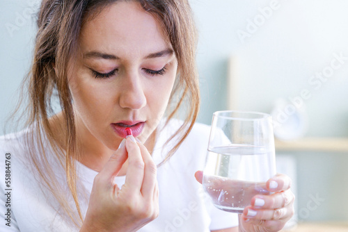 Young woman taking medication at home.