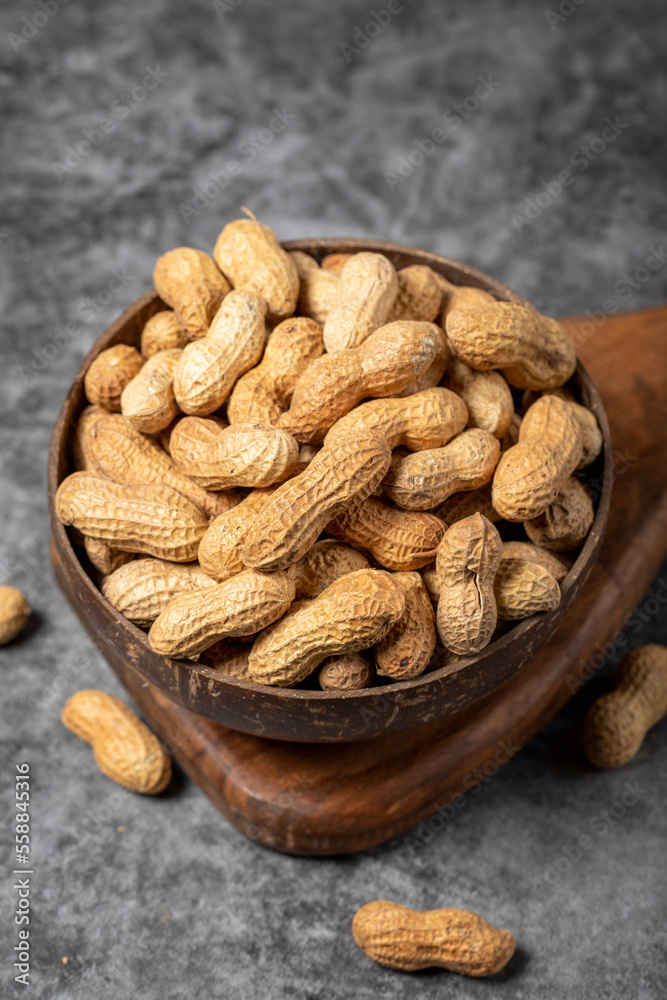 Peanuts in shell on dark background. Peanuts in a coconut bowl. close up Peanuts in shell on dark background. Peanuts in a coconut bowl. close up