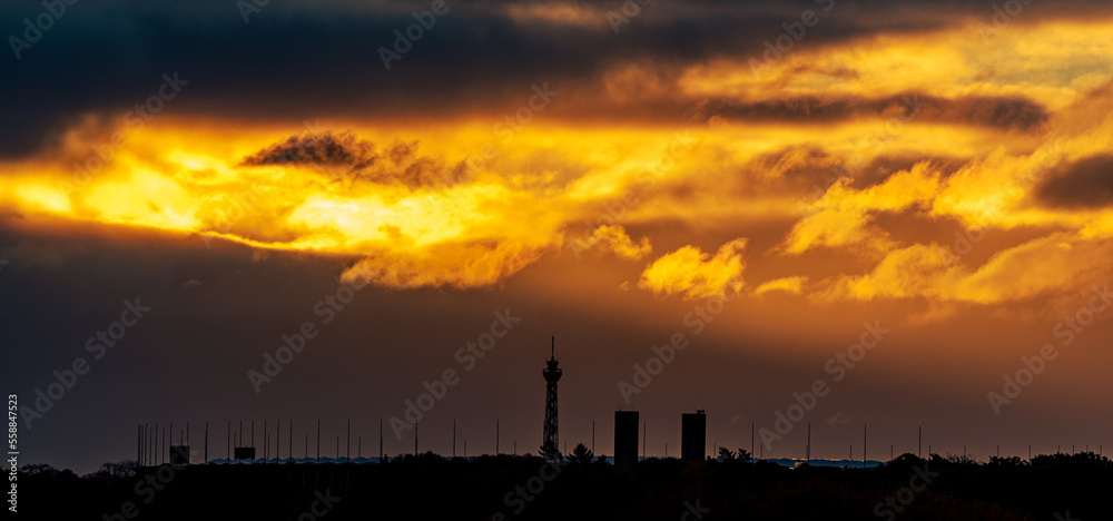 Sonnenstrahlen brechen über dem Olympiastation und dem Messeturm in Berlin durch die Wolken.