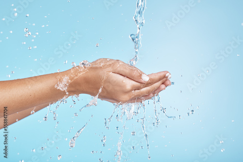 Woman hands, water splash and clean wellness, skincare and personal hygiene, health and shower on studio blue background. Closeup water drops, stream and washing hands, palm and cleaning body in bath