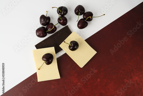 Photos Flat lay of English Morello Cherries with white and dark chocolate on a mixed wh