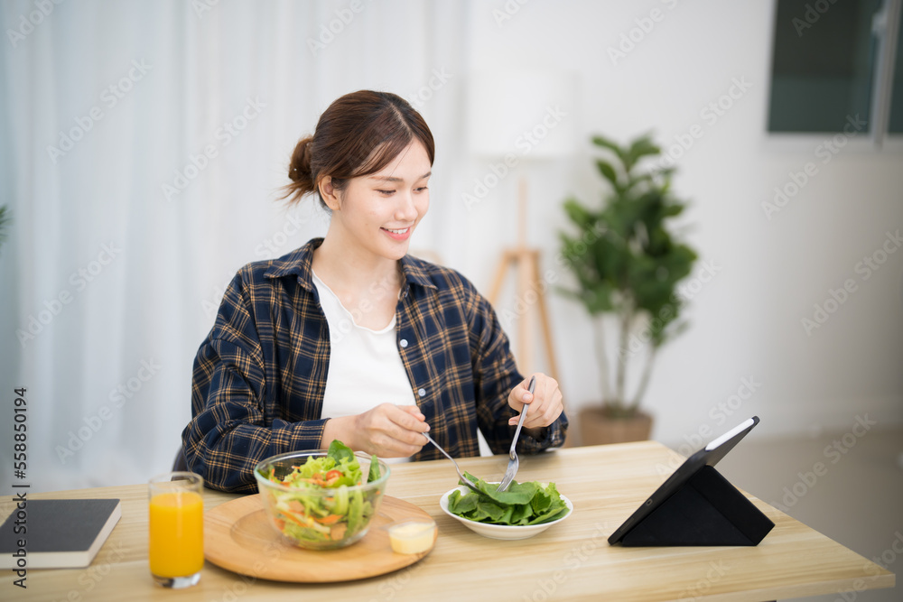 Happy beautiful Asian woman eating healthy food with vegan.salad in the kitchen at home. Happy beautiful Asian woman eating healthy food with vegan.salad in the kitchen at home.
