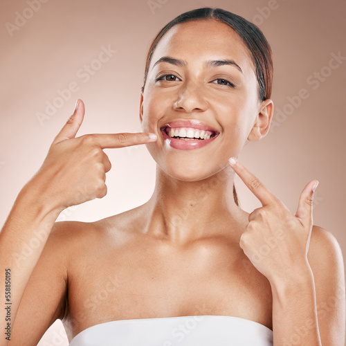 Smile  face and woman pointing to teeth on studio background for wellness  aesthetic beauty or cosmetics. Portrait of model  dental health and showing clean mouth  fresh breath and happy oral results