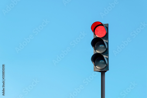 Modern traffic light with red light in front of cloudless sunny blue sky photo