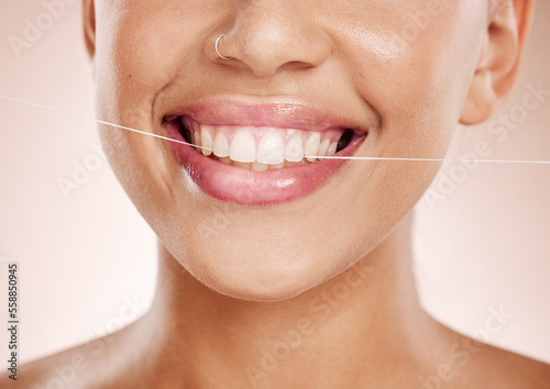 Floss, woman and smile with dental care, clean mouth and after brushing teeth against studio background. Oral health, Latino female and girl with string, fresh breath and morning routine for hygiene