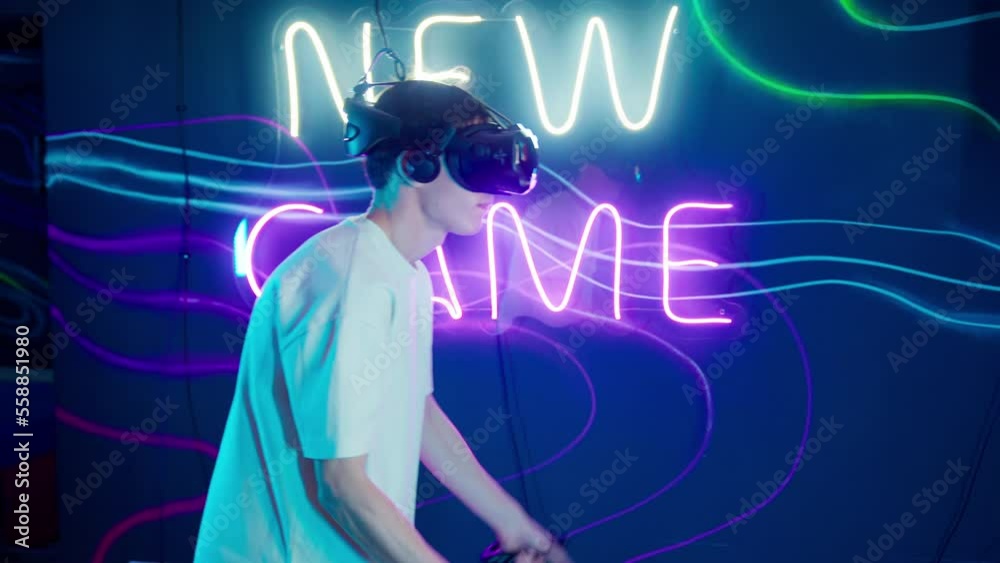 Cyber gamer in VR glasses plays virtual reality game in neon futuristic space. Cyberpunk fashion gaming concept. Man and woman play metaverse virtual digital technology game control with VR goggle. Cyber gamer in VR glasses plays virtual reality game in neon futuristic space. Cyberpunk fashion gaming concept. Man and woman play metaverse virtual digital technology game control with VR goggle.