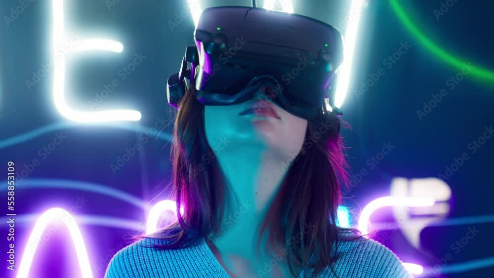 Cyber gamer in VR glasses plays virtual reality game in neon futuristic ...