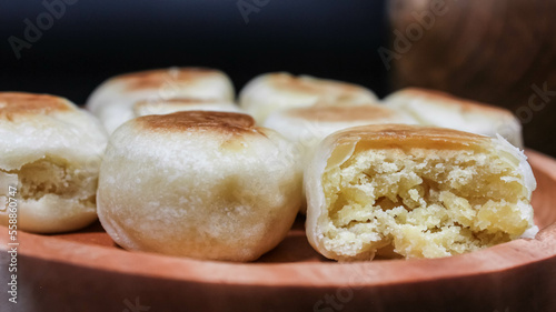 Bakpia Jogja, Bakpia Pathok is a typical Yogyakarta food made from a mixture of green beans, which is wrapped in flour, then baked. Selective focus. Served in wooden plate. Isolated Black Background.