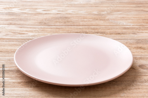 Perspective view of empty pink plate on wooden background. Empty space for your design