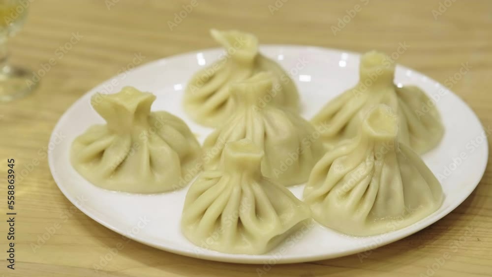 Georgian cuisine. Khinkali or dumplings are boiling in boiled water on the stove in a saucepan. Cooking process. Chef taking khinkali out of the pan. Georgian cuisine. Khinkali or dumplings are boiling in boiled water on the stove in a saucepan. Cooking process. Chef taking khinkali out of the pan.