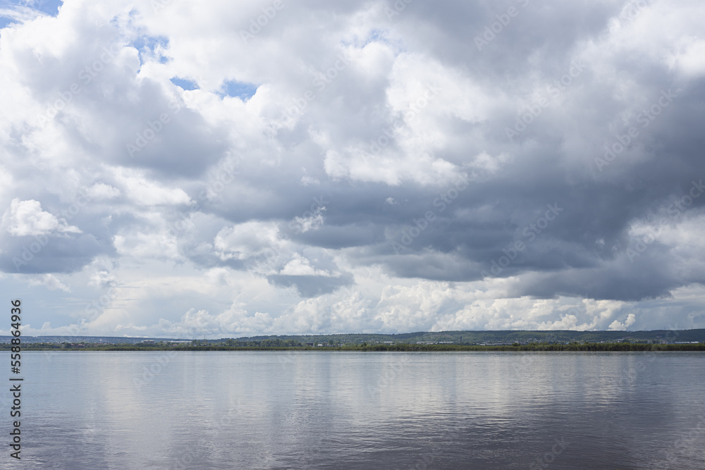 Bright cloudy landscape with shiny white fluffy clouds in sunlight above calm river water with reflection and thin horizon line in minimal style. Softness and serenity in beautiful outdoors scene.