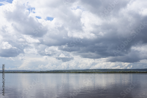 Fototapeta Naklejka Na Ścianę i Meble -  Bright cloudy landscape with shiny white fluffy clouds in sunlight above calm river water with reflection and thin horizon line in minimal style. Softness and serenity in beautiful outdoors scene.