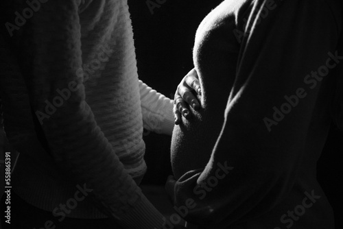 Pregnant girl in a dress holds her hands on her belly 