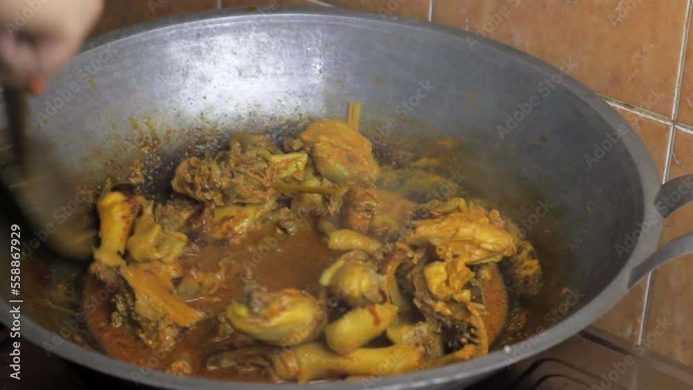 An Indonesian woman is preparing a traditional Indonesian food called chicken rendang, made from chicken with spices An Indonesian woman is preparing a traditional Indonesian food called chicken rendang, made from chicken with spices