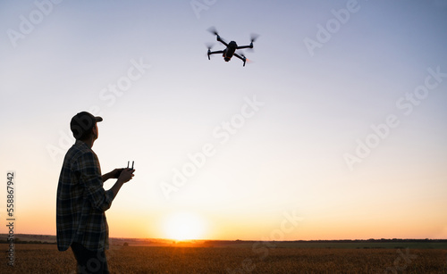 Farmer controls drone sprayer with a tablet on a sunset. Smart farming and precision agriculture 