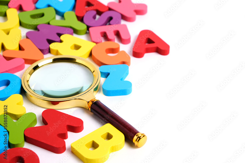 Fototapeta premium Magnifying glass and bright multicolored letters English alphabet white background.