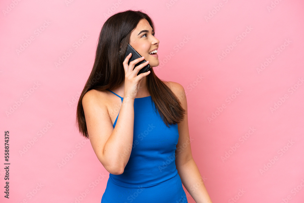 Young Brazilian woman isolated on pink background keeping a conversation with the mobile phone with someone Young Brazilian woman isolated on pink background keeping a conversation with the mobile phone with someone