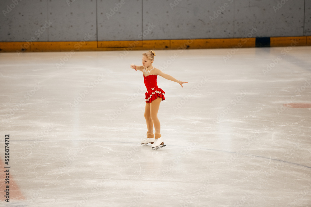 a little girl in a red dress participates in a figure skating competition
