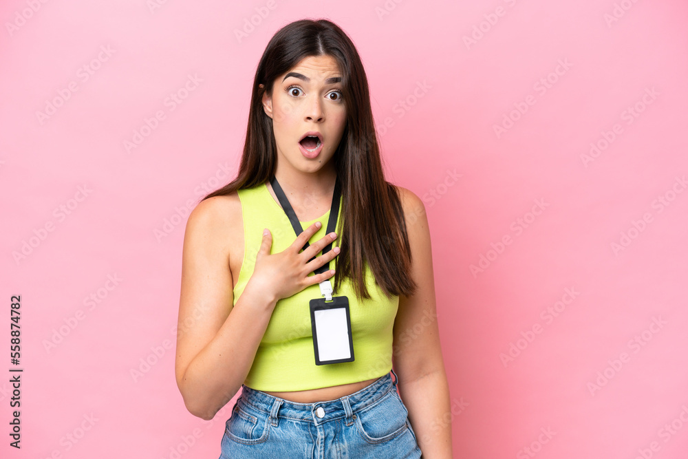 Young Brazilian woman with ID card isolated on pink background surprised and shocked while looking right Young Brazilian woman with ID card isolated on pink background surprised and shocked while looking right