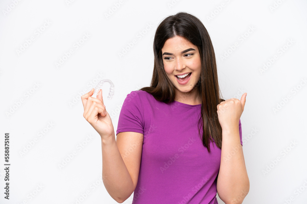 Young Brazilian woman holding invisible braces isolated on white background celebrating a victory Young Brazilian woman holding invisible braces isolated on white background celebrating a victory
