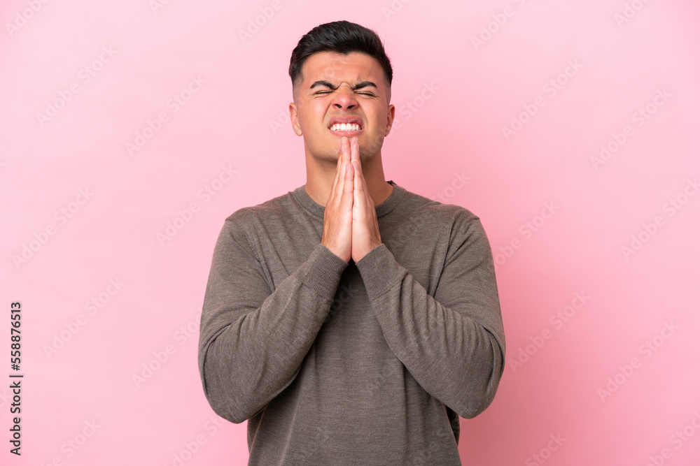 Young caucasian handsome man isolated on pink background keeps palm together. Person asks for something Young caucasian handsome man isolated on pink background keeps palm together. Person asks for something