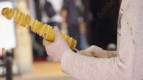 Street vendor preparing Tornado Potato on skewer - popular street food photo