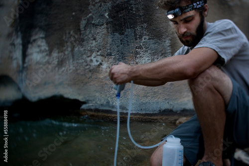 A man with a headlamp pumps water from a river in Utah. photo