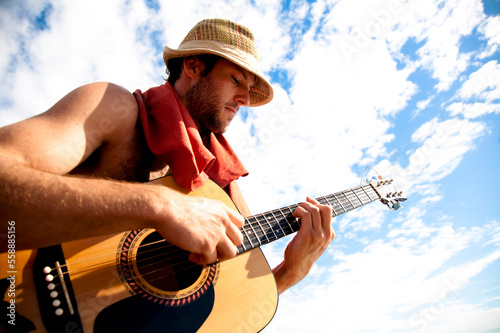 A young man plays his guitar while on a fishing boat off the coast of Malakati, Fiji. photo