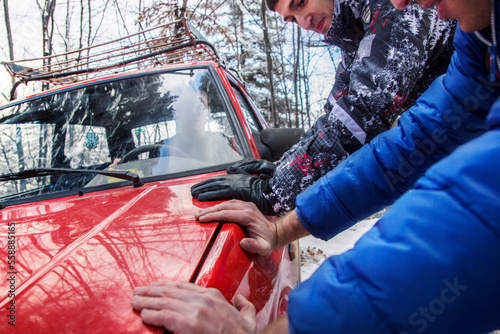 Two men pushing a red car sideways photo