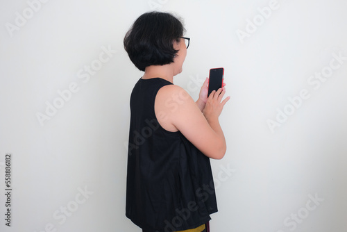 Rear view of a woman dialing her smartphone in her hand to make a call photo