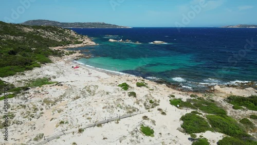 Tourist people relax and swim at white sandy beach at La Maddalena Island, Sardinia - Aerial 4k photo