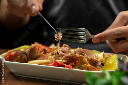man eats lamb stew on the bone with vegetables. Khashlama is popular Armenian dish, which is prepared from beef with vegetables. Khashlama in the plate. caucasian food