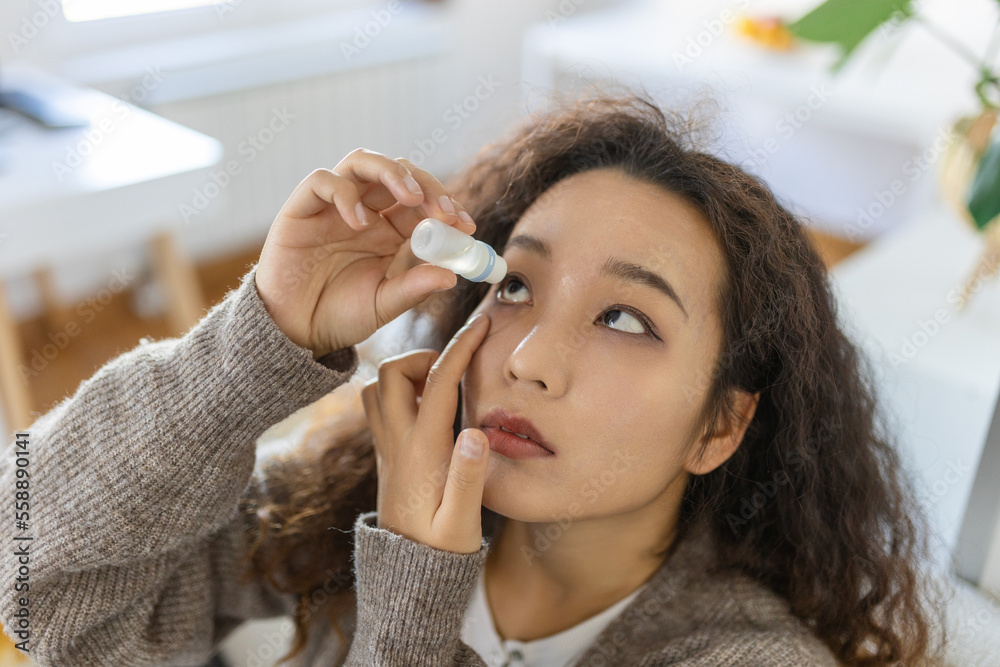 Asian Woman using eye drop, woman dropping eye lubricant to treat dry