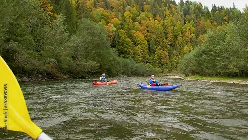 A happy entusiastic males in blue inflatables canoes having a fun ride in calm waters of a river. Extreme sport photo