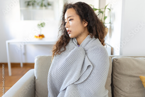 Bild auf Leinwand Sick young Asian woman feeling cold covered with blanket sit on bed, ill black g