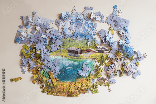 uncompleted landscape puzzle, jigsaw pieces. mountains and lake. leisure activity