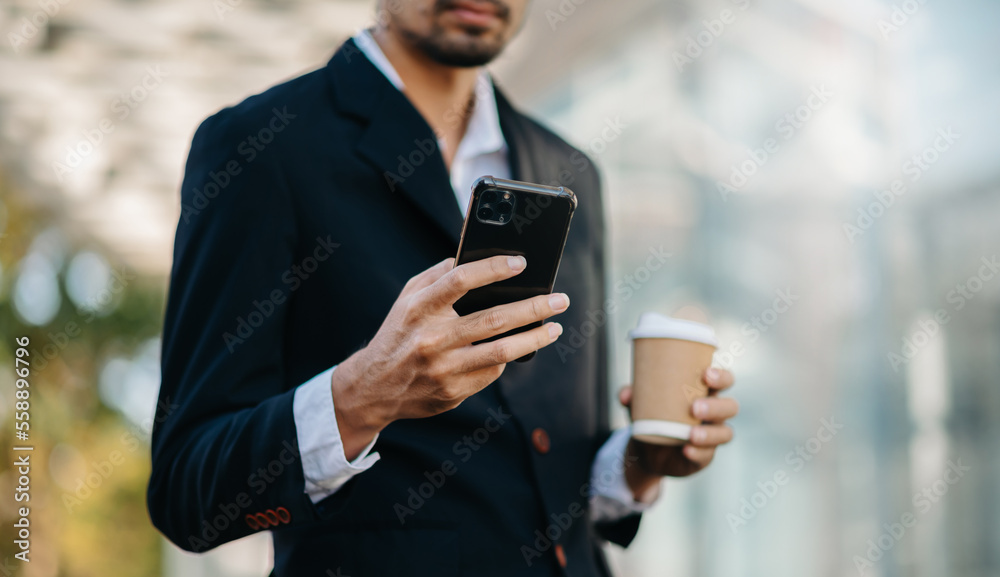 Asian businessman using digital tablet, smartphone and holding coffee to go while working at office Asian businessman using digital tablet, smartphone and holding coffee to go while working at office