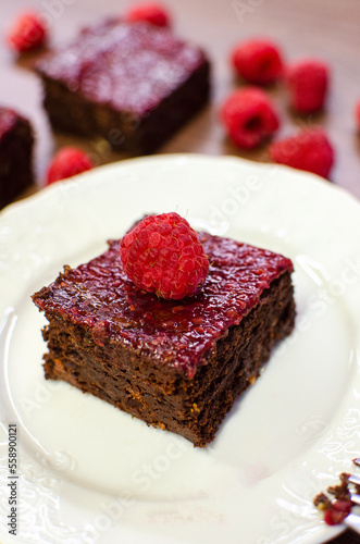 Chocolate brownies with raspberries on white plate 
