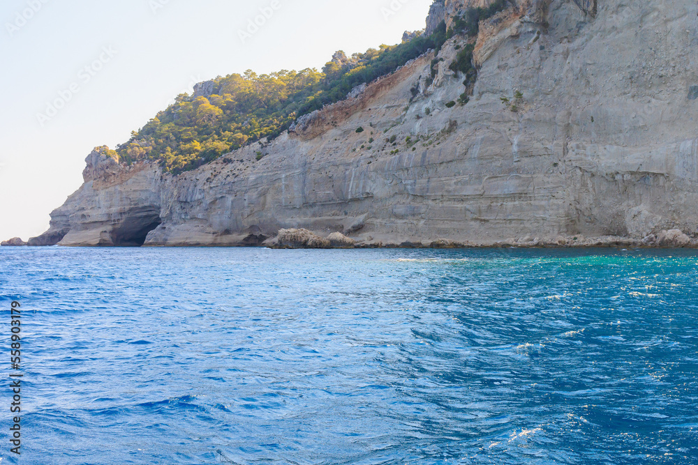 View of the rocky shore from the sea. Mediterranean Sea in Turkey. Popular tourist places. Background View of the rocky shore from the sea. Mediterranean Sea in Turkey. Popular tourist places. Background