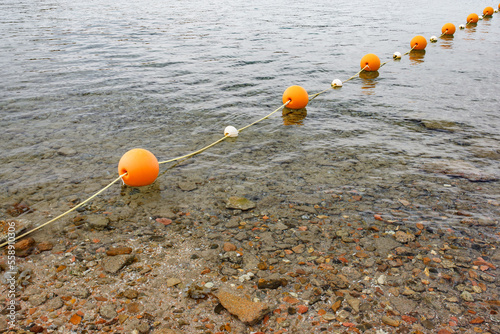 Orange spherical buoys on a rope in the sea, fencing a safe swimming area photo